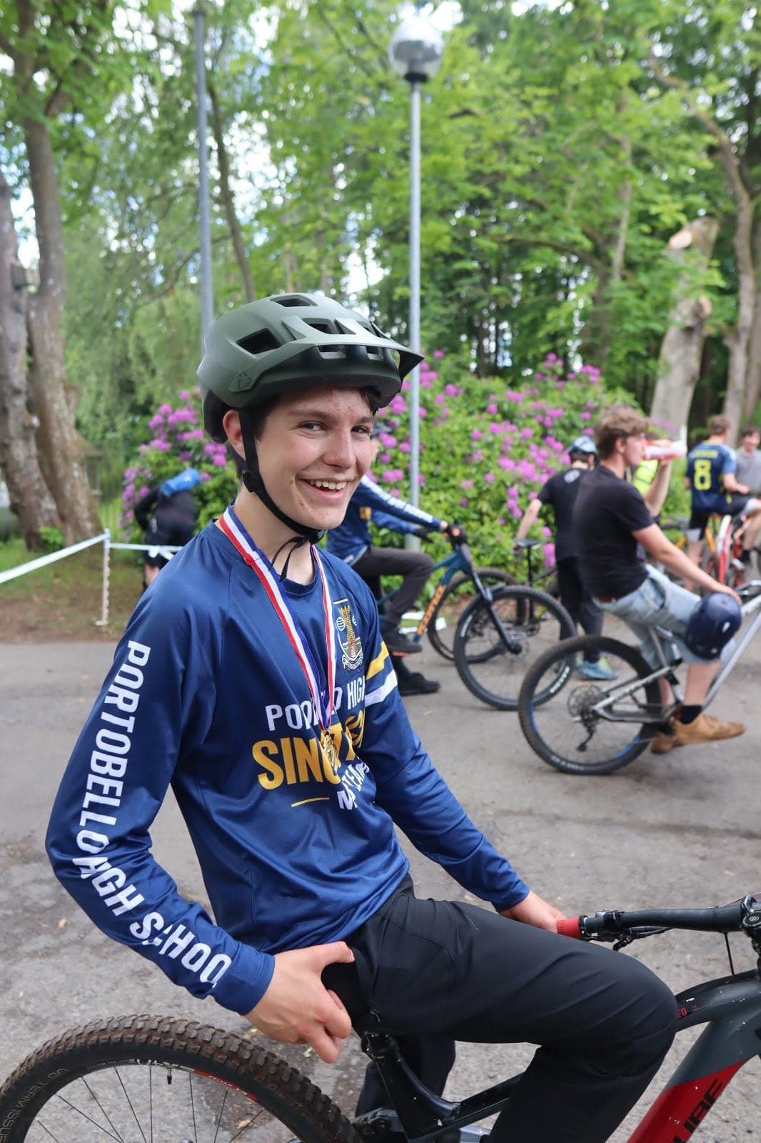 Smiling mountain bike rider wearing the custom team jersey and medal